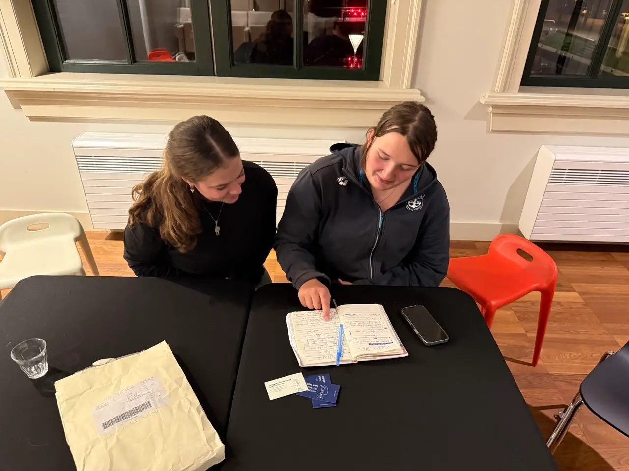 Twee leden van de JAR aan tafel tijdens een vergadering, bezig met aantekeningen in een notitieboek.